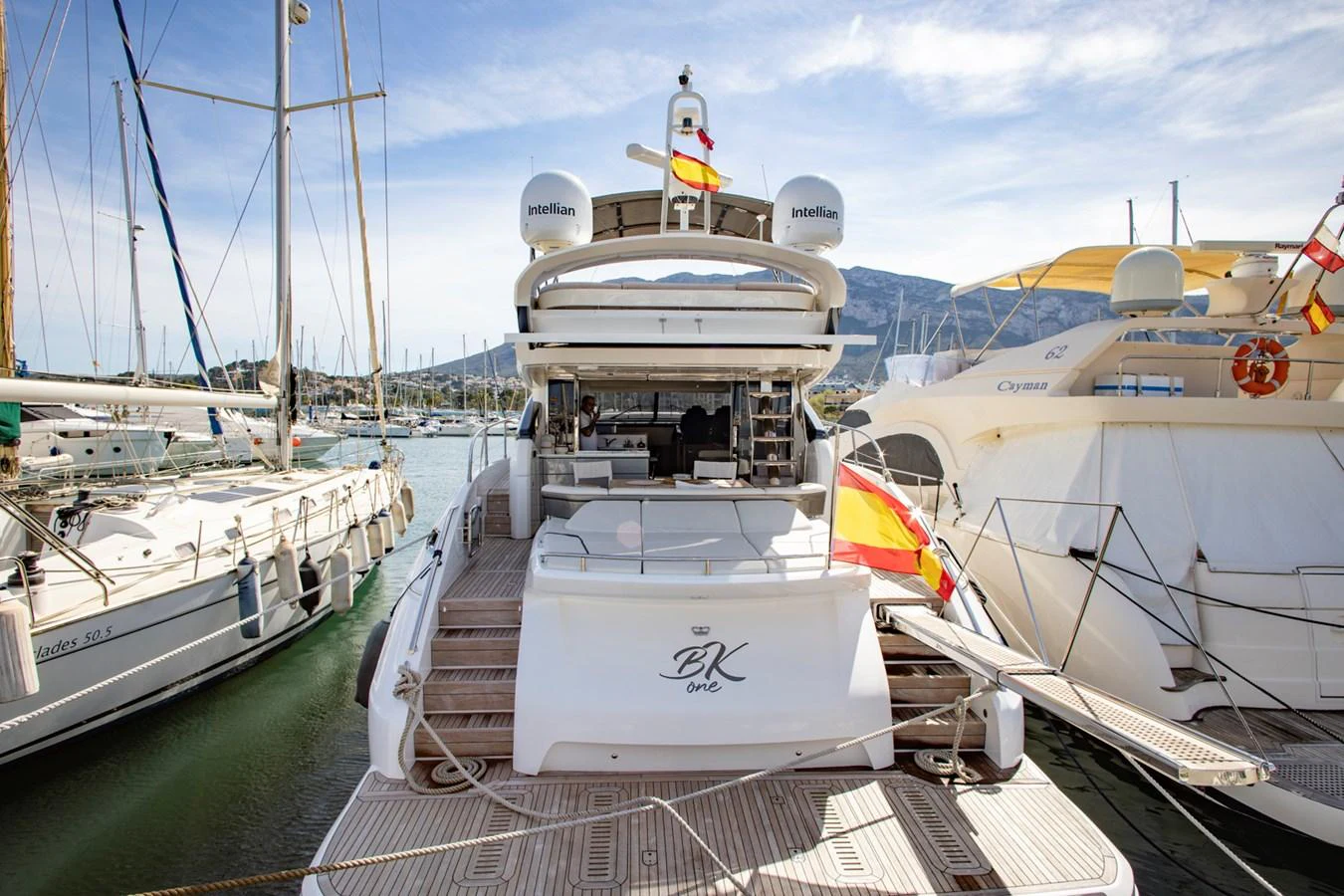 The yacht's aft deck is shown docked in a marina, featuring a spacious layout with a view of surrounding boats. aboard BK ONE Yacht for Sale