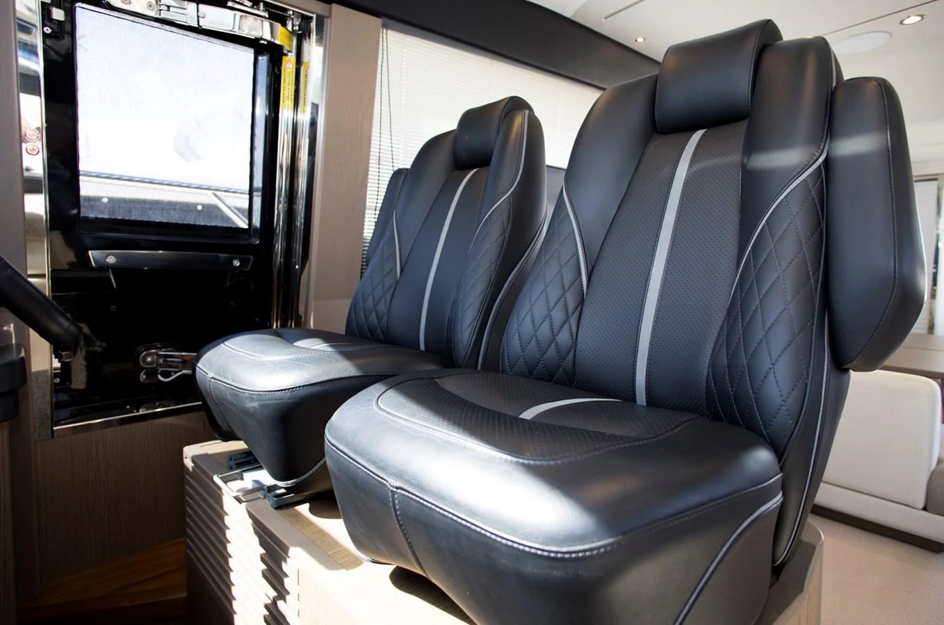 The image showcases the luxurious helm seating area with plush, black leather seats. aboard BK ONE Yacht for Sale