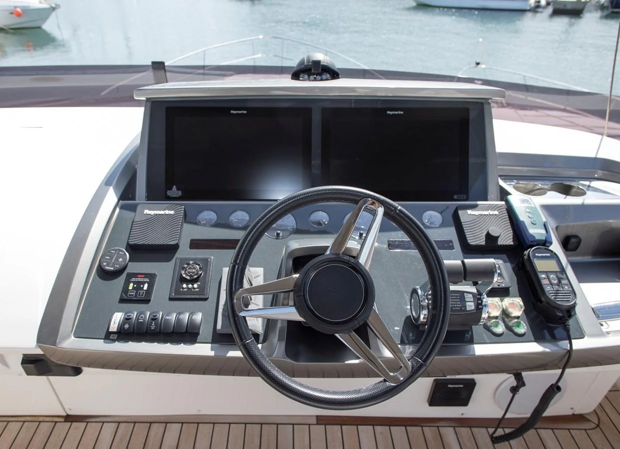 The helm station features advanced navigation equipment and a sleek steering wheel, set against a backdrop of serene waters. aboard BK ONE Yacht for Sale