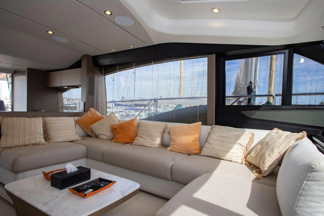 The salon features a spacious seating area with plush cushions and large windows offering a view of the marina. aboard BK ONE Yacht for Sale