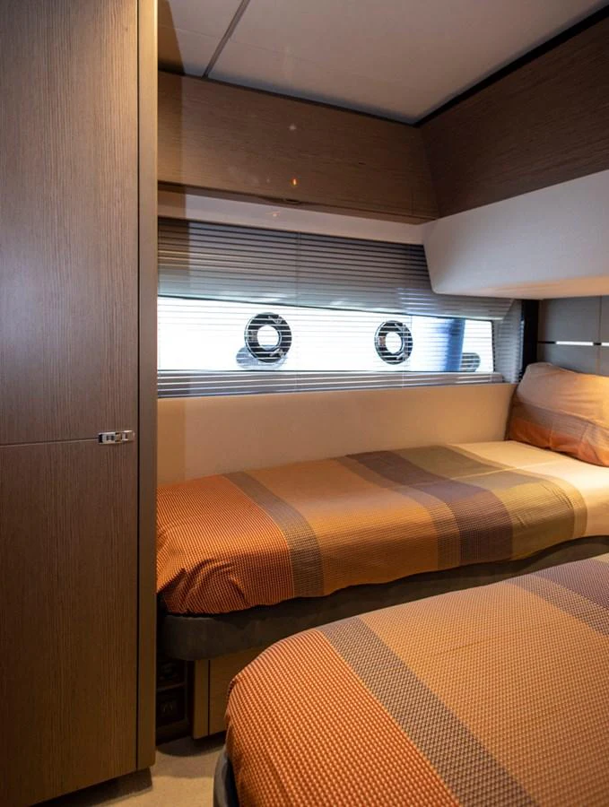 The guest stateroom features twin beds with cozy bedding and natural light from the portholes. aboard BK ONE Yacht for Sale