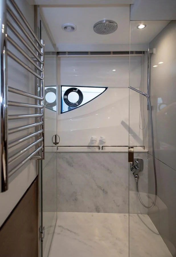 A sleek and modern yacht bathroom with a glass-enclosed shower and marble accents. aboard BK ONE Yacht for Sale