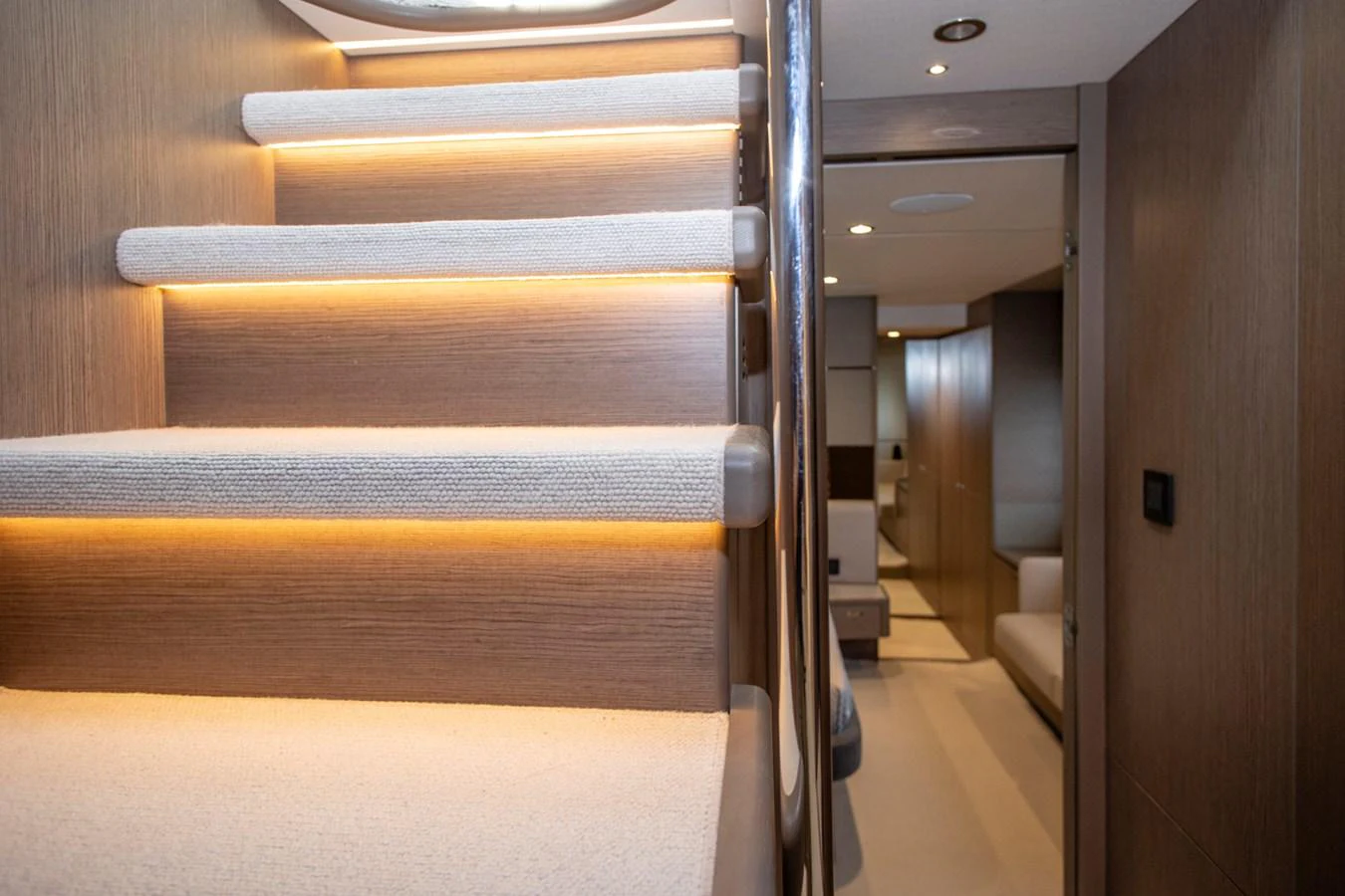 A modern yacht interior featuring a well-lit staircase leading to a cozy lower deck area. aboard BK ONE Yacht for Sale