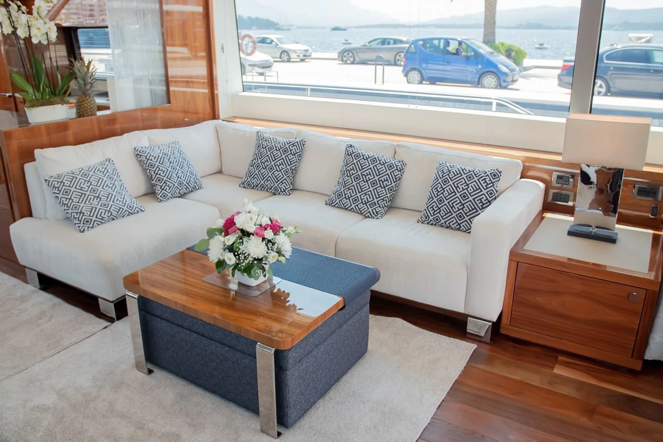 The yacht's salon features a comfortable white sectional sofa with patterned pillows and a wooden coffee table adorned with a floral arrangement. aboard SUNSEEKER 76Y Yacht for Sale