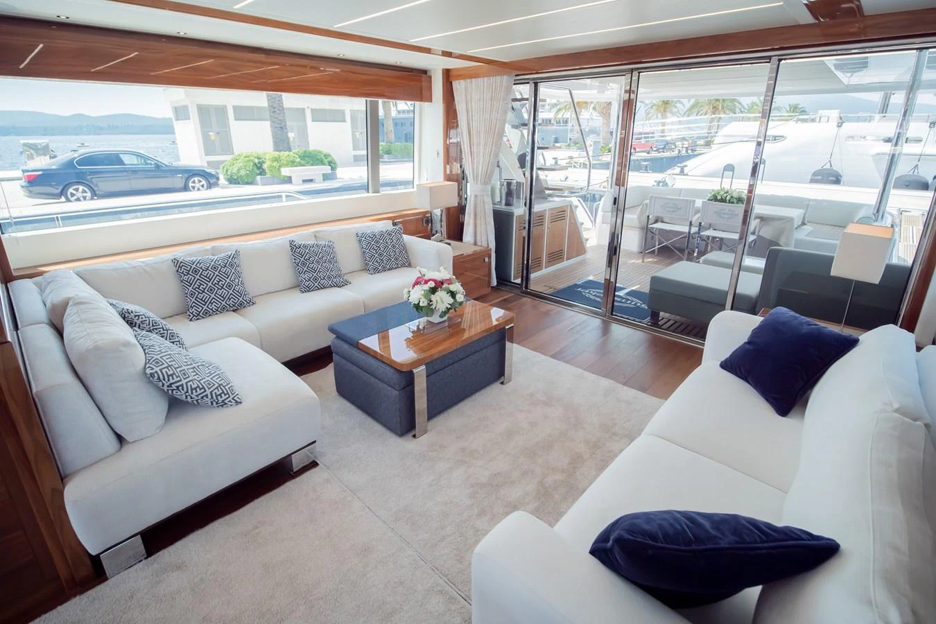 The salon features plush seating, elegant decor, and large windows offering a view of the marina. aboard SUNSEEKER 76Y Yacht for Sale