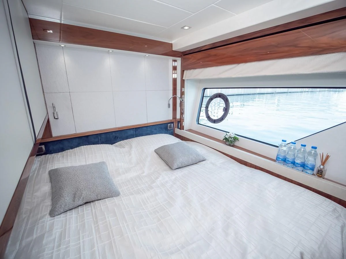 A cozy stateroom with a large bed and a window offering a view of the water. aboard SUNSEEKER 76Y Yacht for Sale