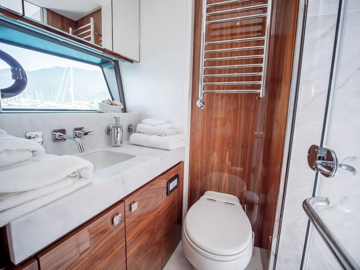 The yacht's bathroom features elegant wood paneling, a modern sink, and a glass-enclosed shower. aboard SUNSEEKER 76Y Yacht for Sale