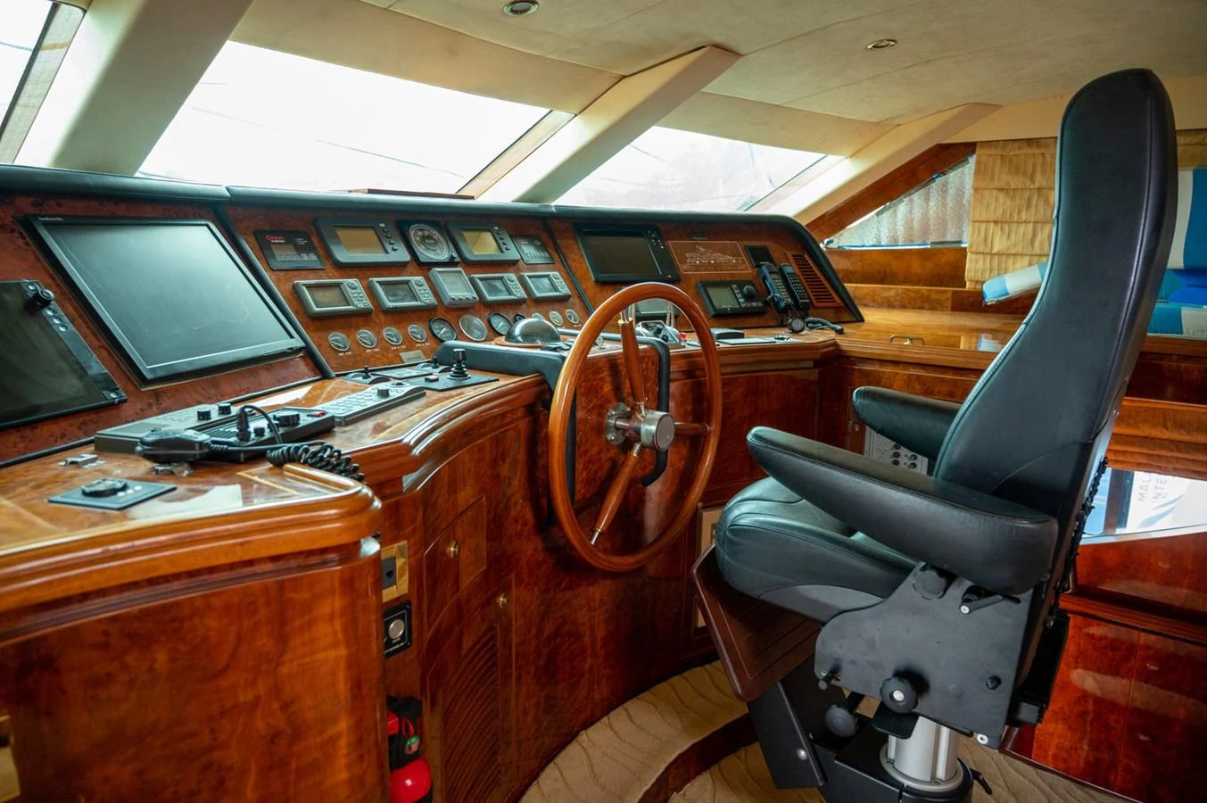 The helm station features a sophisticated control panel with luxurious wood finishes and a comfortable captain's chair. aboard LADY EILEEN Yacht for Sale