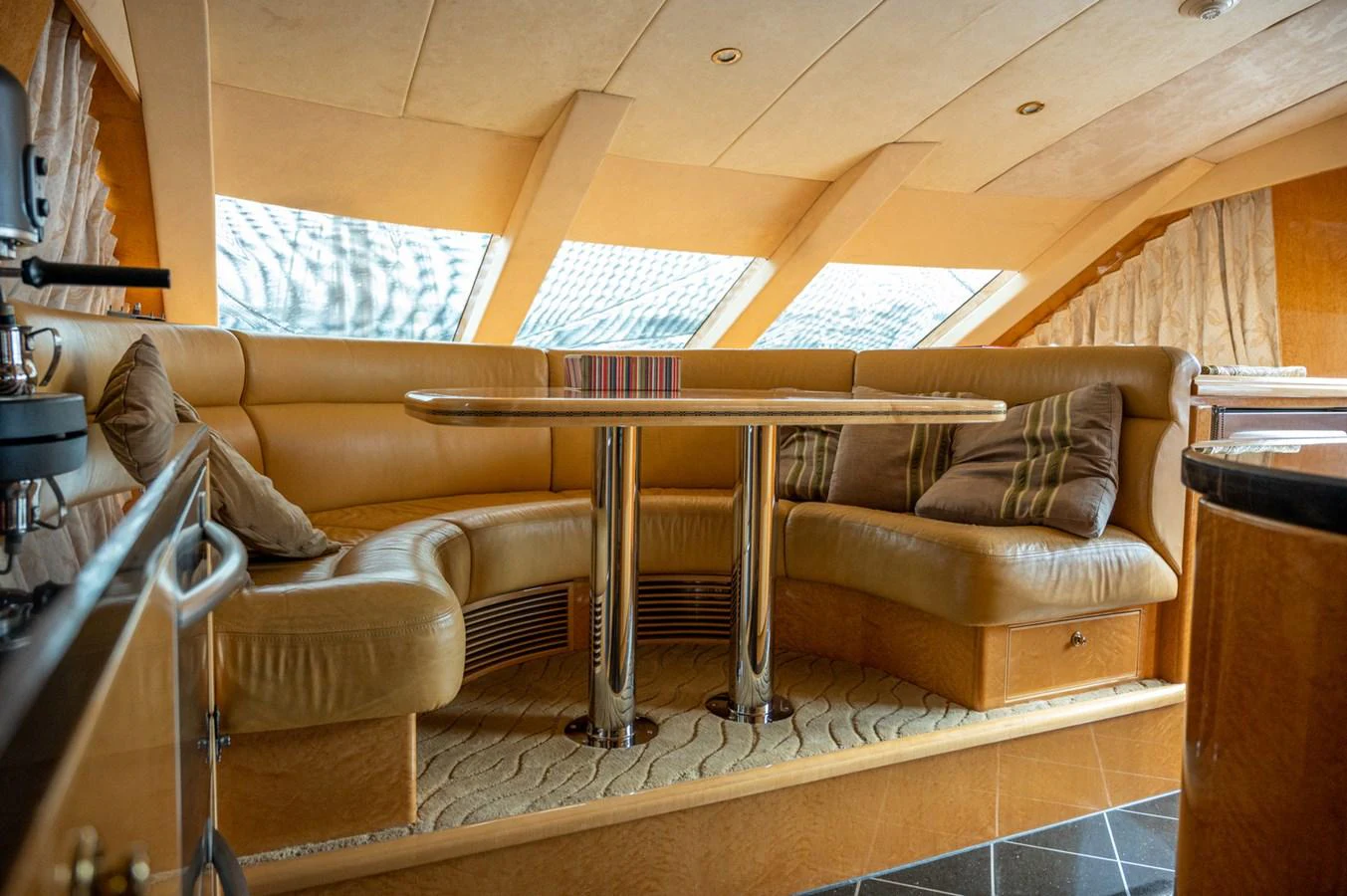 The salon features a cozy seating area with plush leather couches and a polished wooden table, bathed in natural light from large windows. aboard LADY EILEEN Yacht for Sale