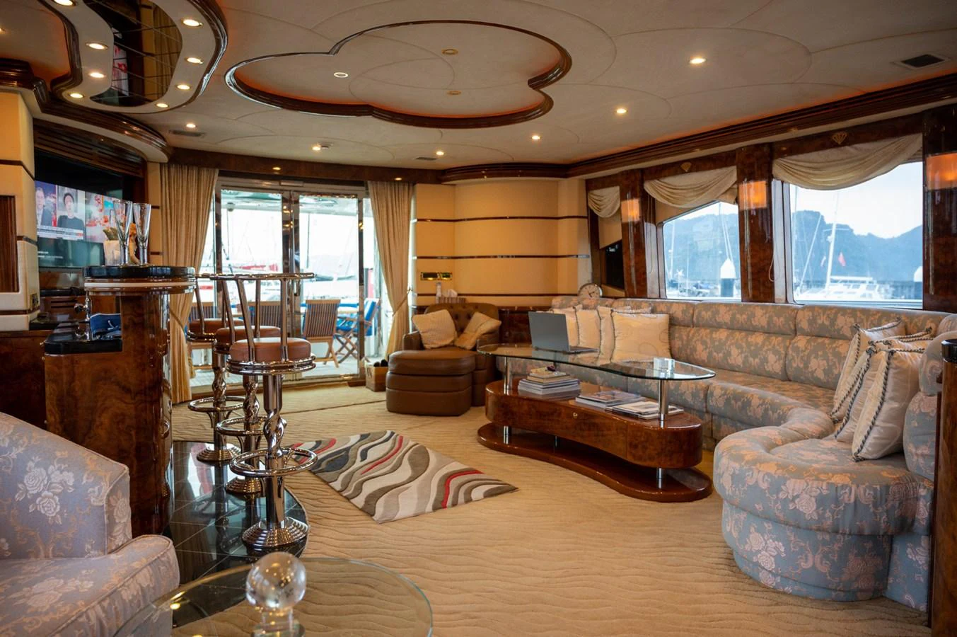The yacht's salon exudes elegance with its plush seating, rich wood accents, and expansive windows offering scenic views. aboard LADY EILEEN Yacht for Sale