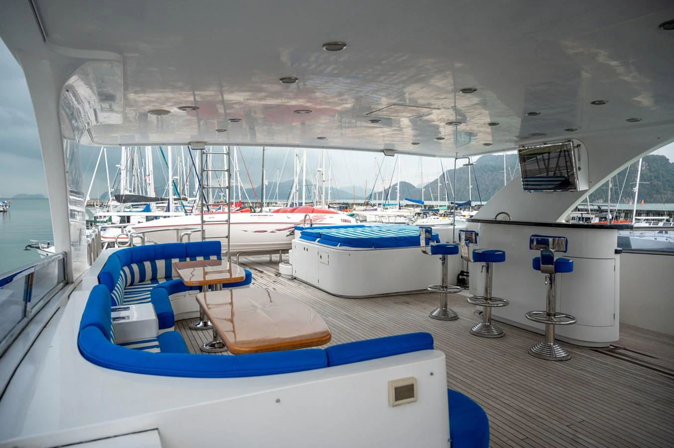 The aft deck features a spacious seating area with blue cushions, a dining table, and a bar with stools, perfect for entertaining. aboard LADY EILEEN Yacht for Sale