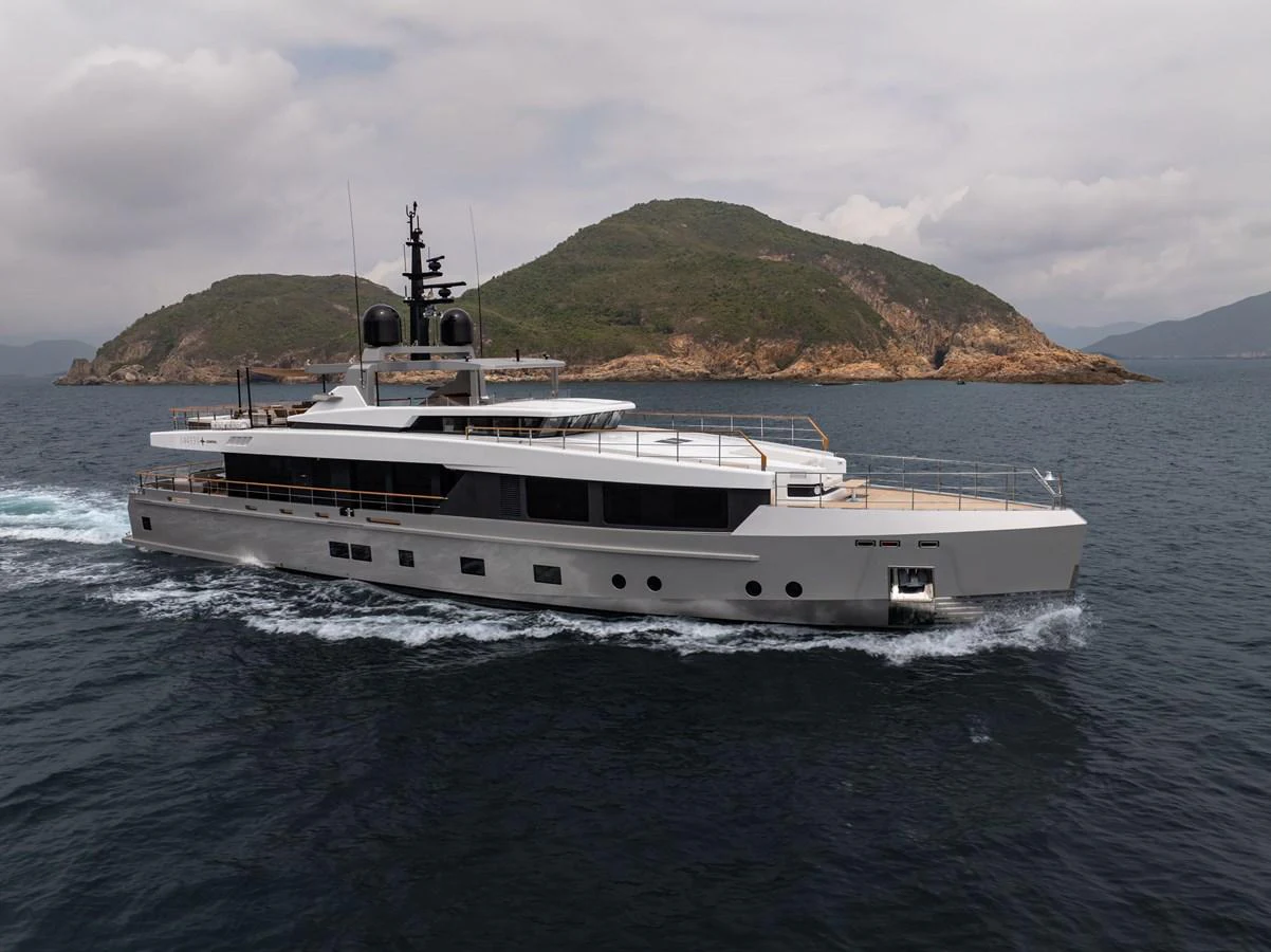 A sleek, modern yacht cruises through calm waters with scenic islands in the background. aboard SUN PRINCE Yacht for Sale