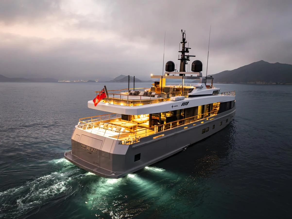 A sleek yacht cruises through calm waters at dusk, illuminated by warm lights. aboard SUN PRINCE Yacht for Sale