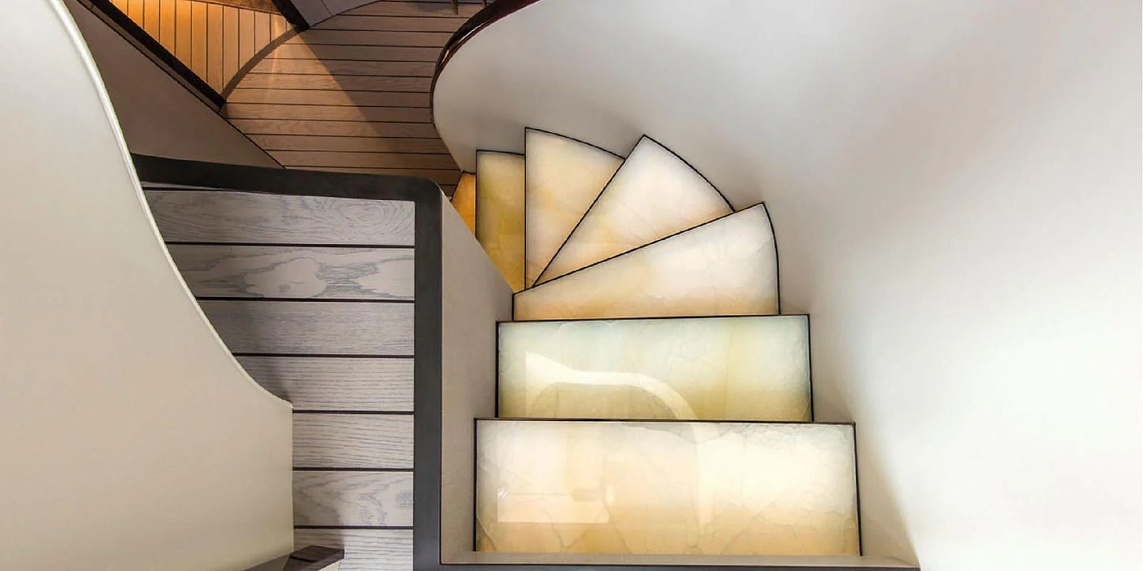 A beautifully designed staircase with illuminated steps and elegant curves. aboard PANTERA Yacht for Sale