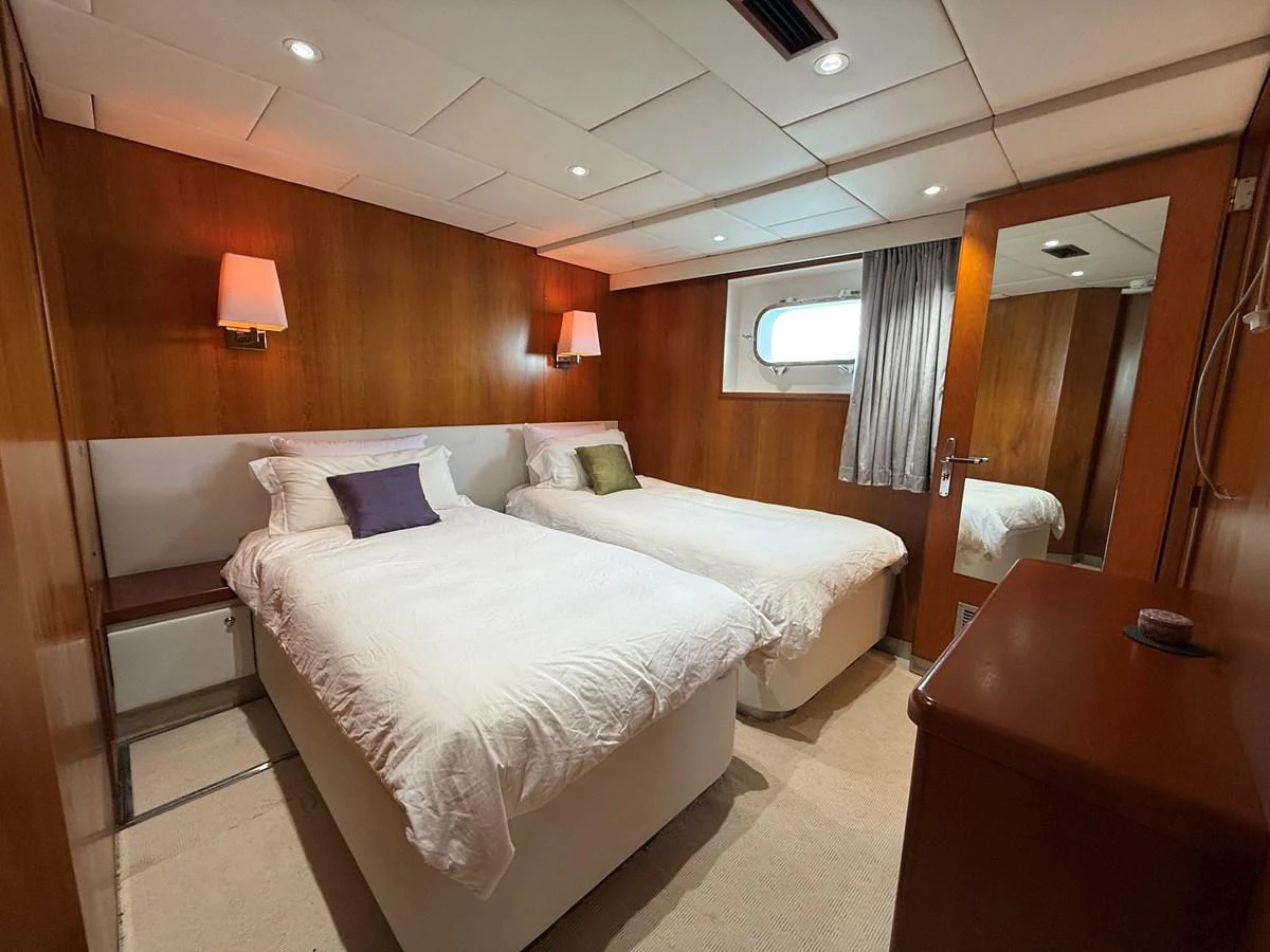 The guest stateroom features twin beds with elegant wooden paneling and soft lighting. aboard LIGAYA Yacht for Sale