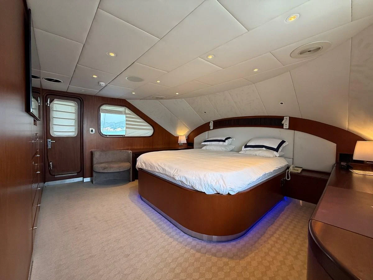 The master stateroom features a spacious bed with elegant wood finishes and ambient lighting. aboard LIGAYA Yacht for Sale