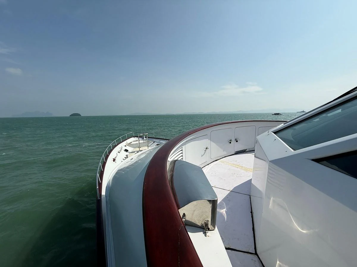 The bow of the yacht is shown cruising through calm waters with a clear sky overhead. aboard LIGAYA Yacht for Sale