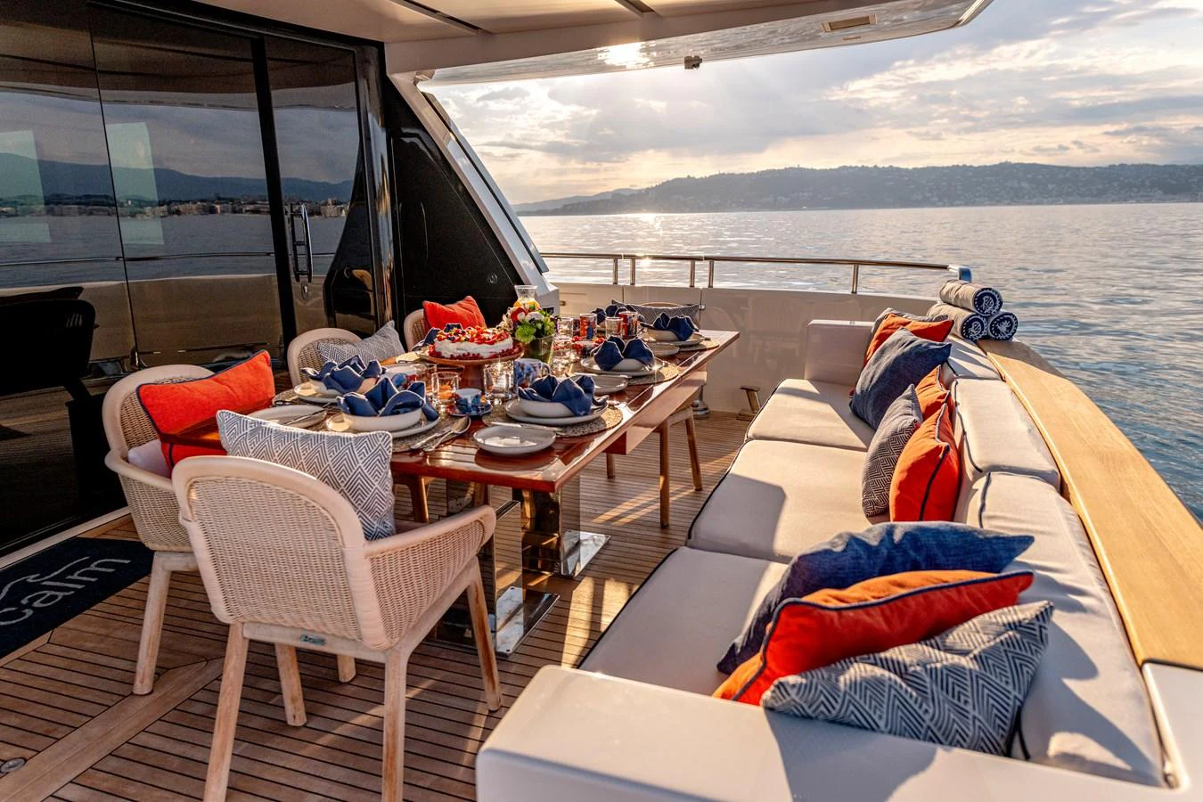 The aft deck features an elegant dining area with a beautifully set table and comfortable seating, perfect for enjoying meals with a view of the sea. aboard CALM Yacht for Sale