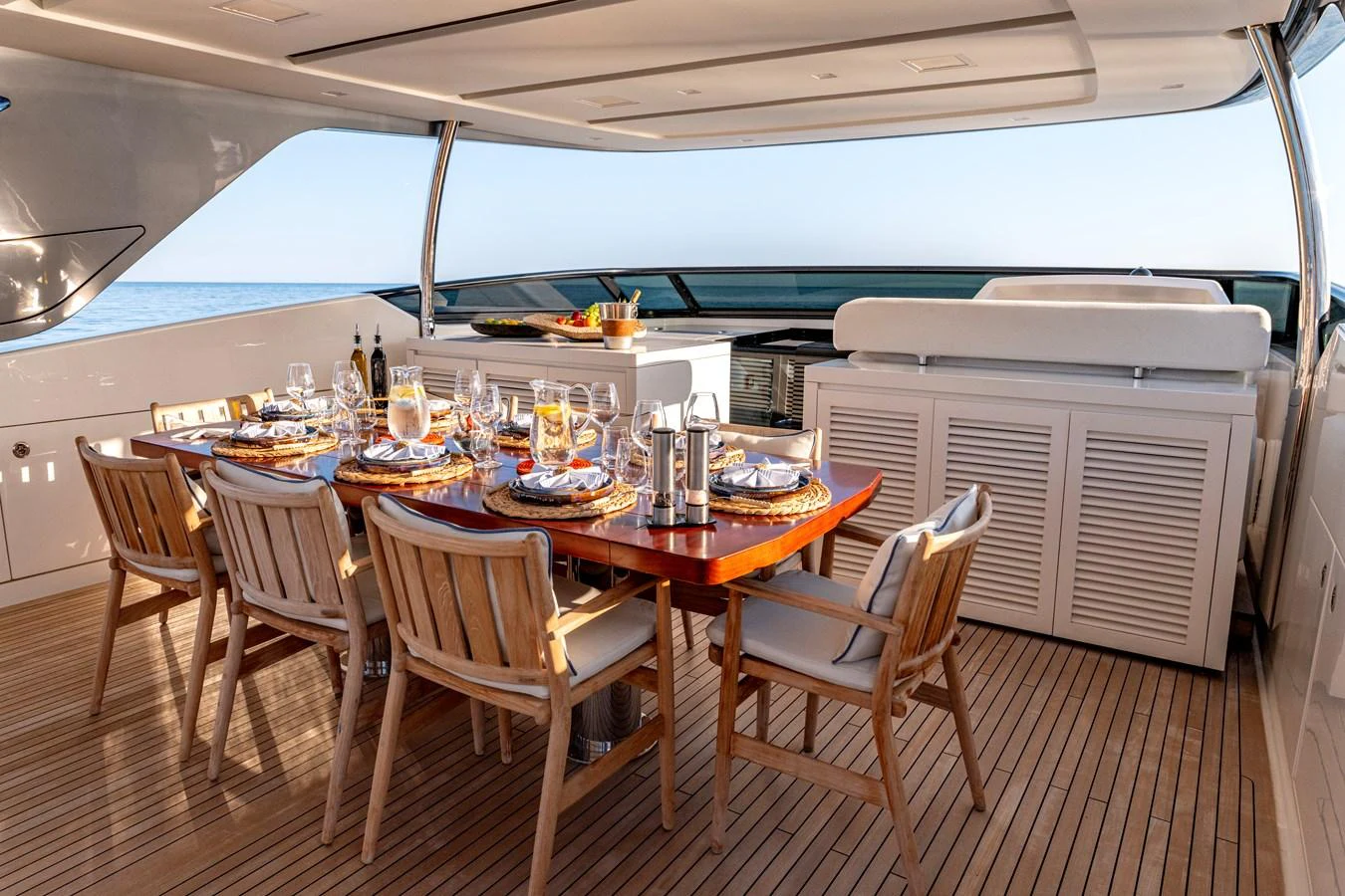 The aft deck features an elegant dining area with a wooden table and comfortable chairs, perfect for alfresco dining. aboard CALM Yacht for Sale