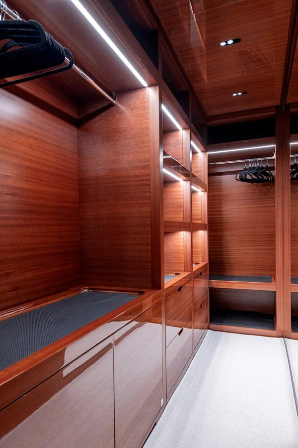 The yacht features a spacious and well-lit wooden closet with ample storage space. aboard CALM Yacht for Sale