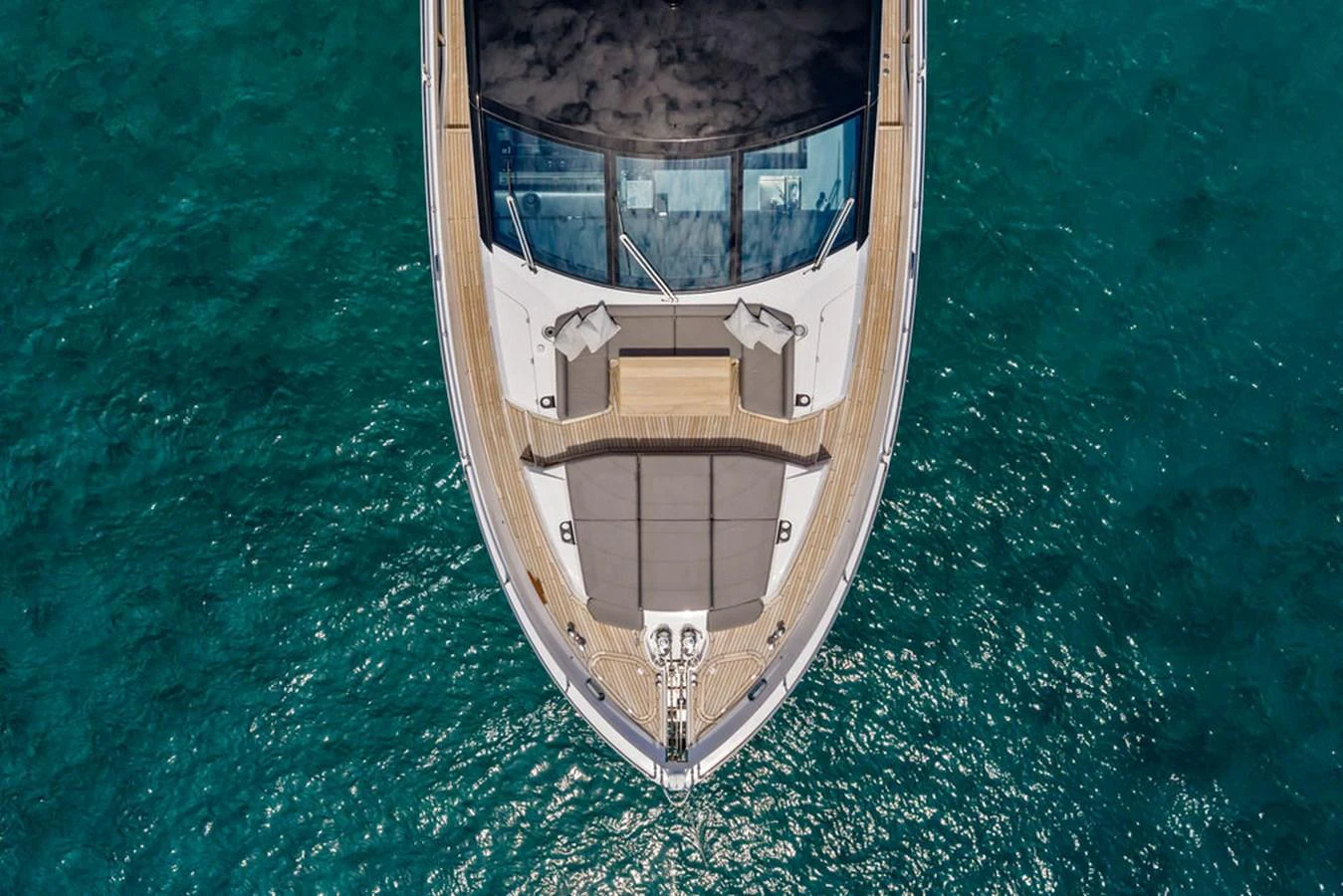 The yacht's bow features a spacious sunbathing area with plush cushions, set against the backdrop of clear blue waters. aboard DOLCE FAR NIENTE Yacht for Sale
