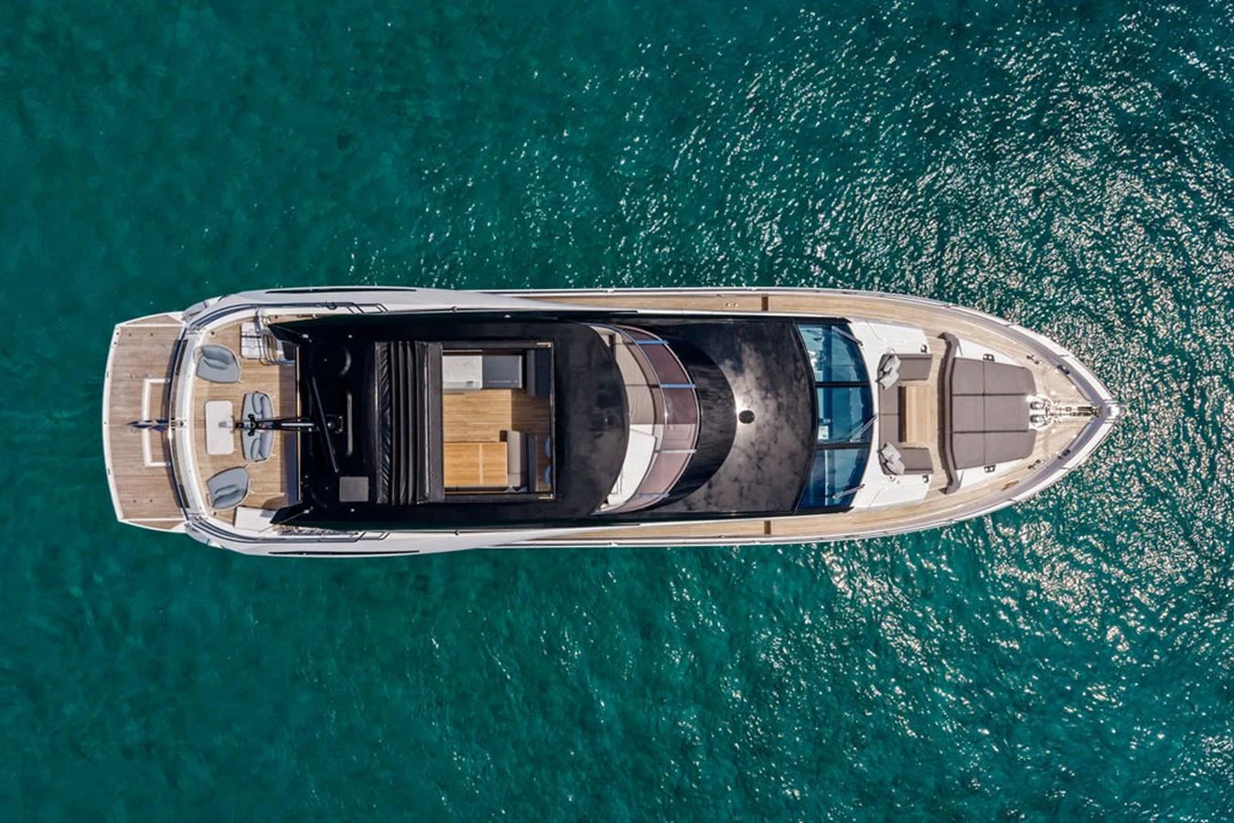 A sleek yacht glides over clear blue waters, showcasing its elegant design from an aerial perspective. aboard DOLCE FAR NIENTE Yacht for Sale