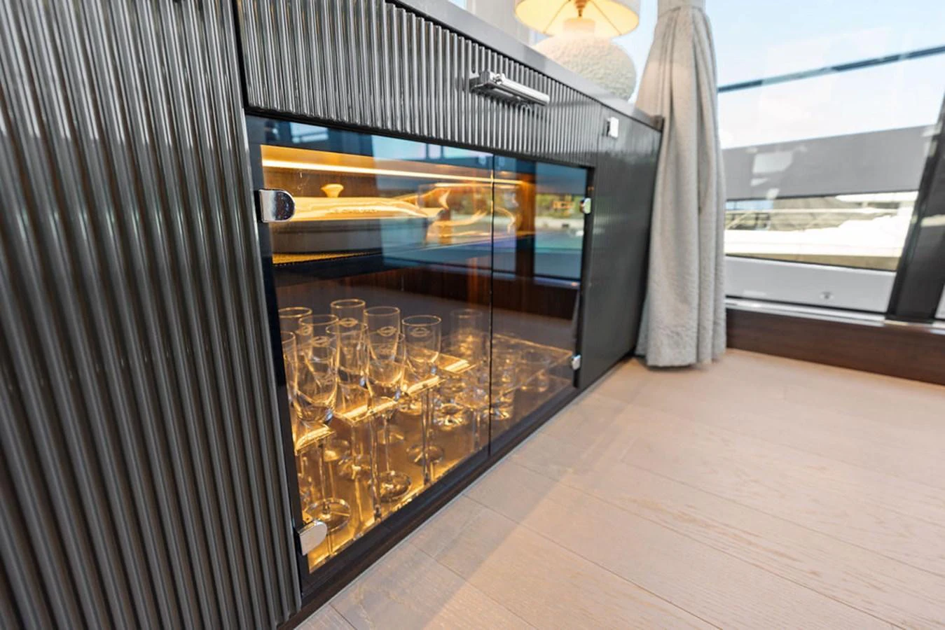 A sophisticated interior cabinet with glassware, illuminated by warm lighting. aboard DOLCE FAR NIENTE Yacht for Sale