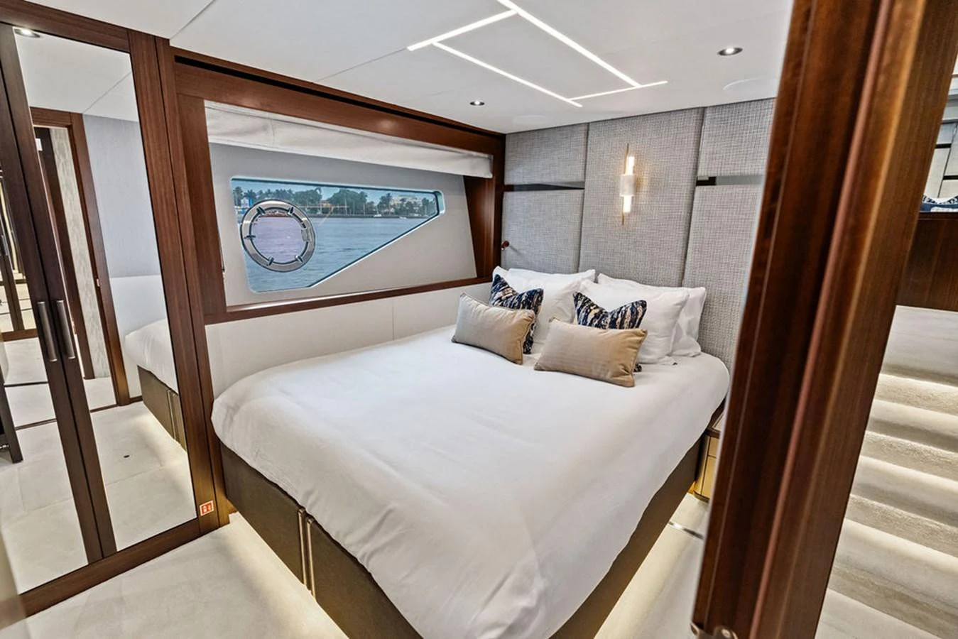 The stateroom features a luxurious bed with elegant decor and a scenic view through the porthole. aboard DOLCE FAR NIENTE Yacht for Sale
