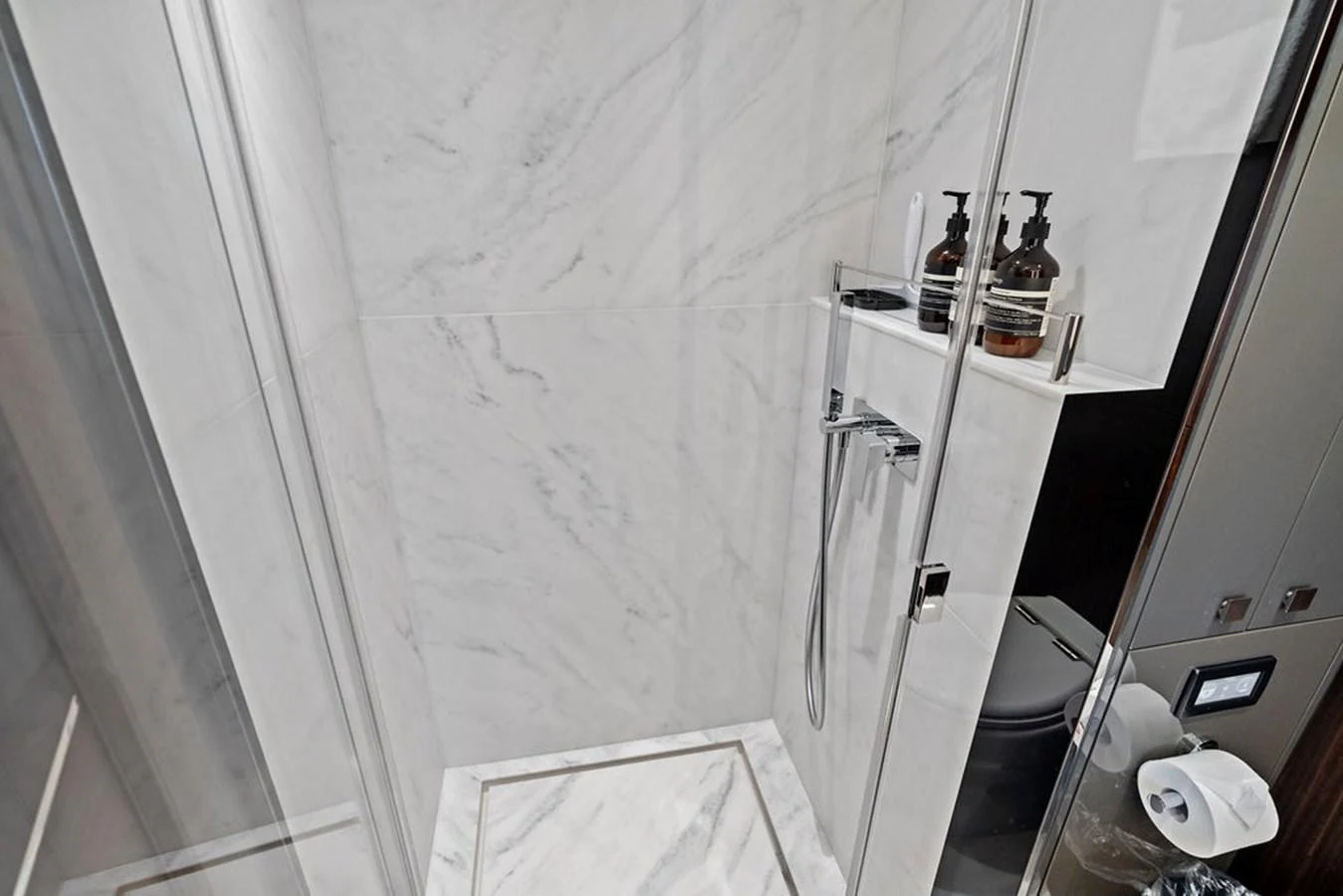 A sleek, modern bathroom with marble walls and a glass shower enclosure. aboard DOLCE FAR NIENTE Yacht for Sale