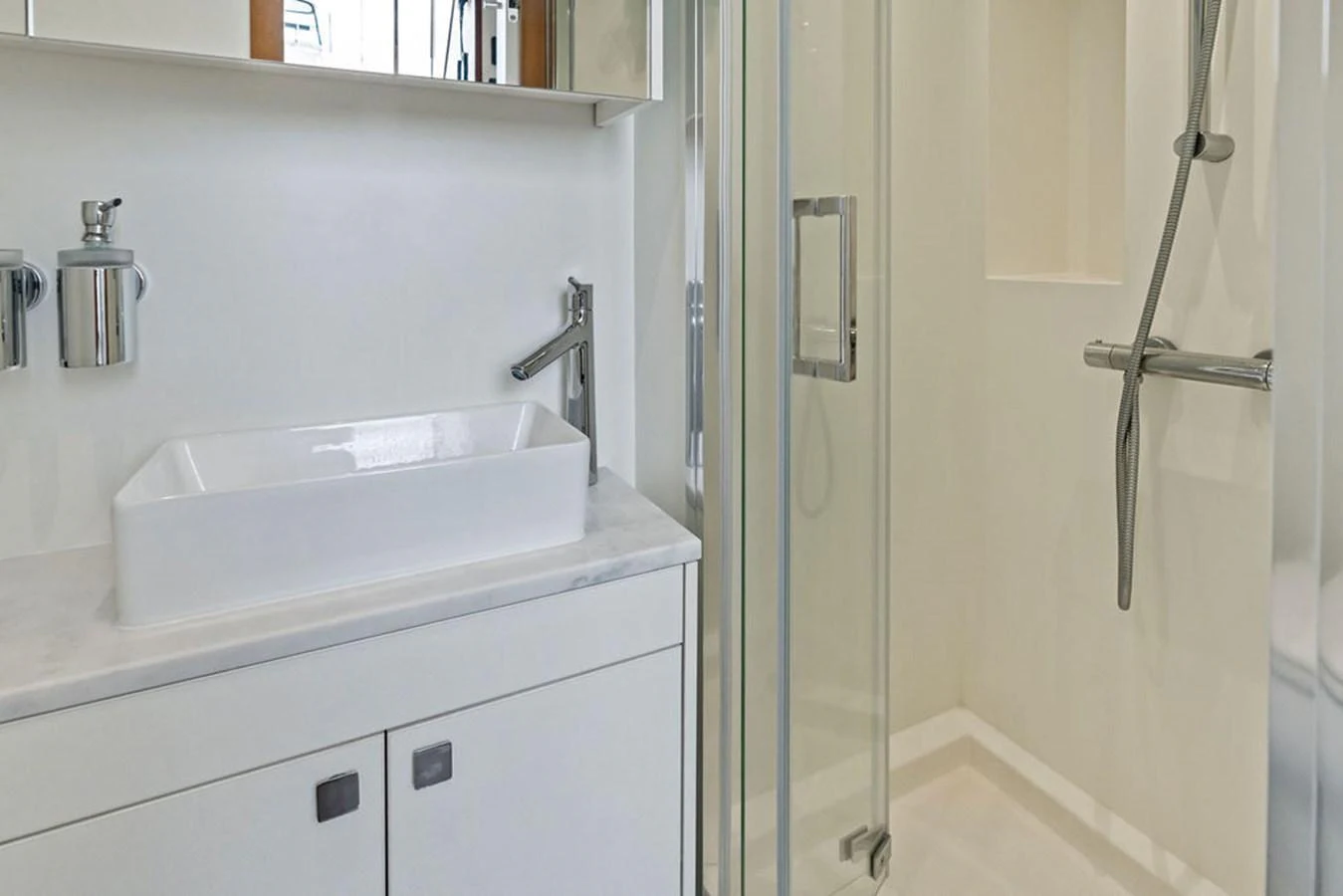 A modern yacht bathroom featuring a sleek sink and a glass-enclosed shower. aboard DOLCE FAR NIENTE Yacht for Sale