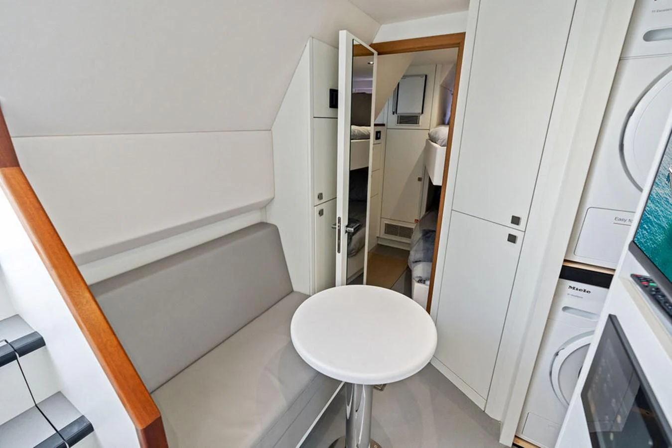 The cozy interior features a compact seating area with a small table, adjacent to a laundry station. aboard DOLCE FAR NIENTE Yacht for Sale