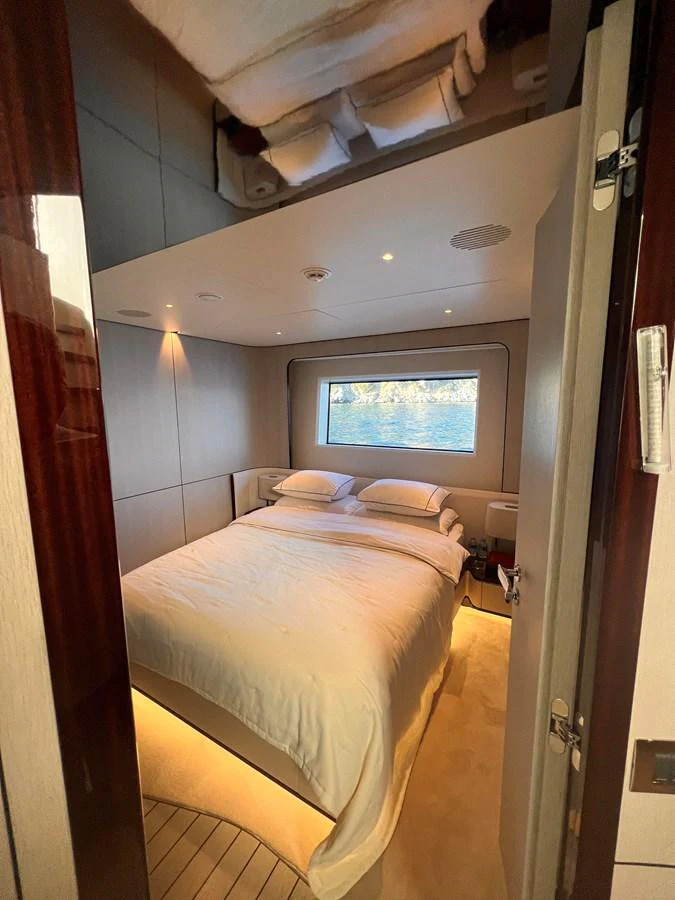 A cozy stateroom with a large window offering a serene view of the water. aboard DAGUSHA V Yacht for Sale