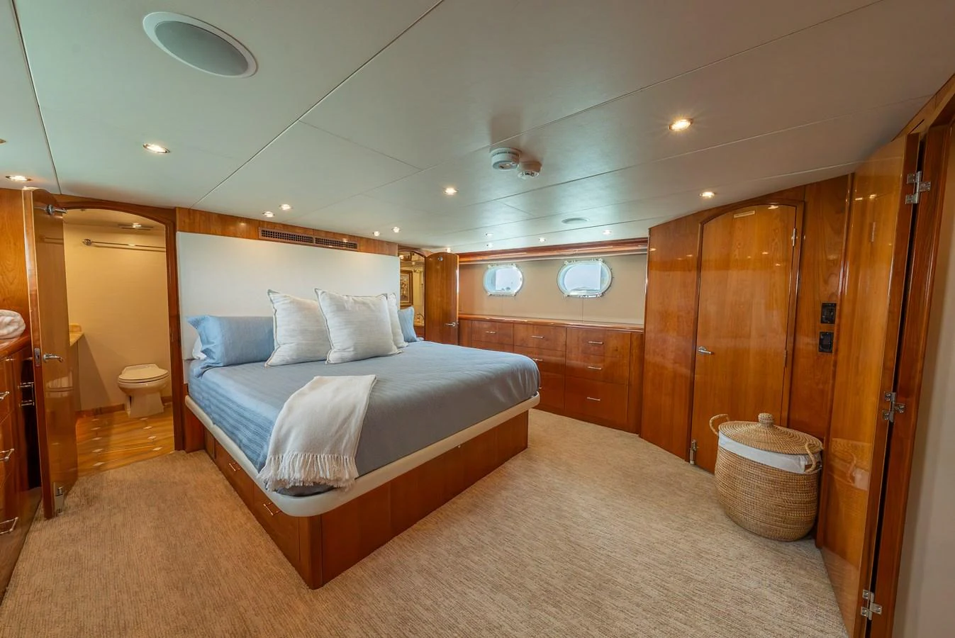 The master stateroom features a spacious bed with elegant wooden cabinetry and soft lighting. aboard HAVILAH Yacht for Sale