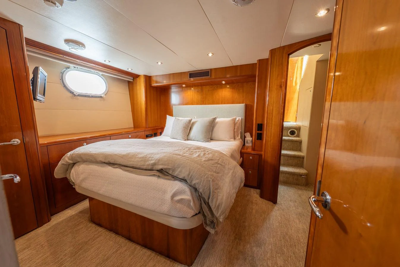 The stateroom features a plush bed with warm wood paneling and soft lighting, creating a cozy and inviting atmosphere. aboard HAVILAH Yacht for Sale