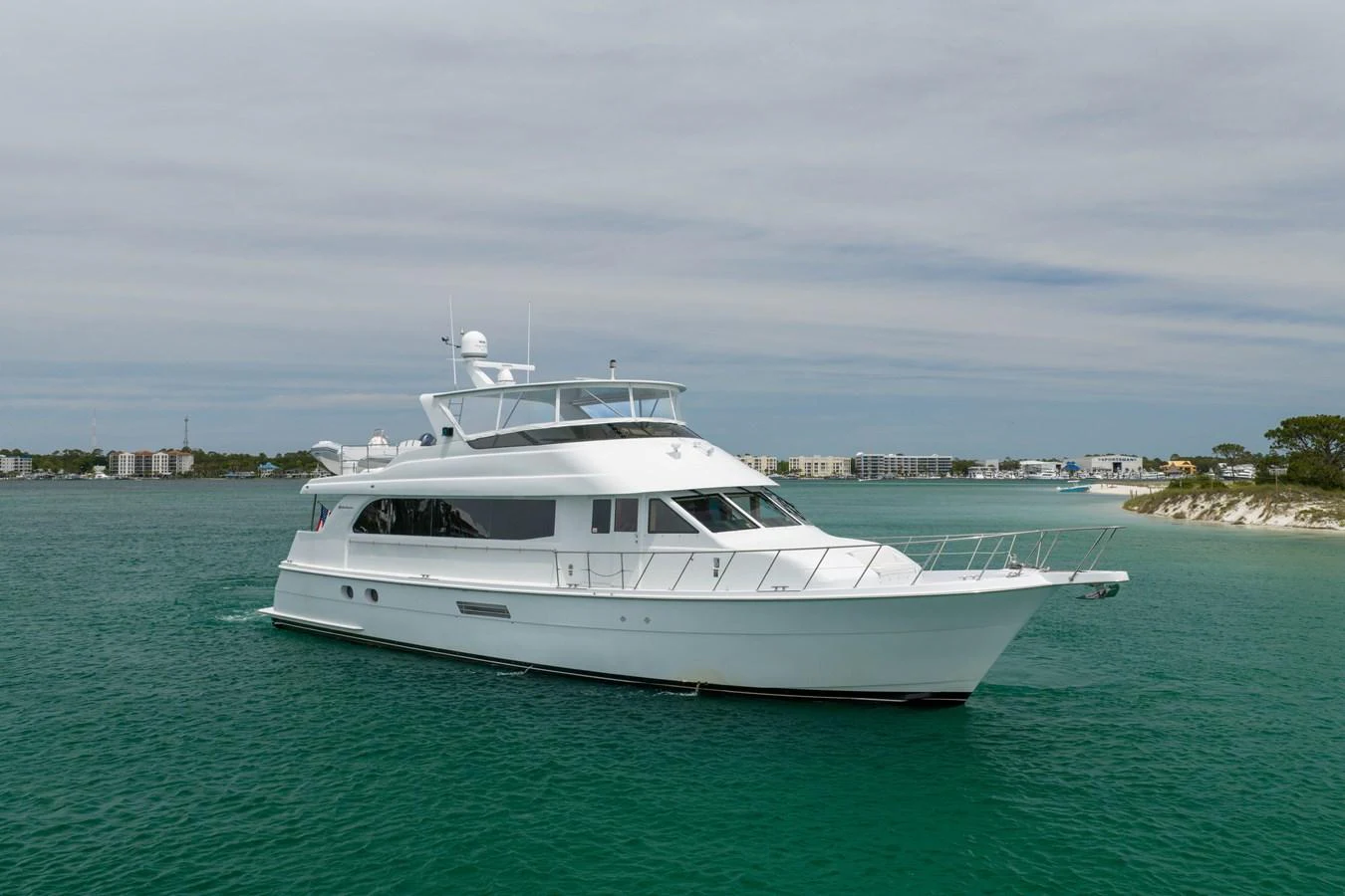 A sleek white yacht cruises gracefully on calm waters with a scenic coastal backdrop. aboard HAVILAH Yacht for Sale