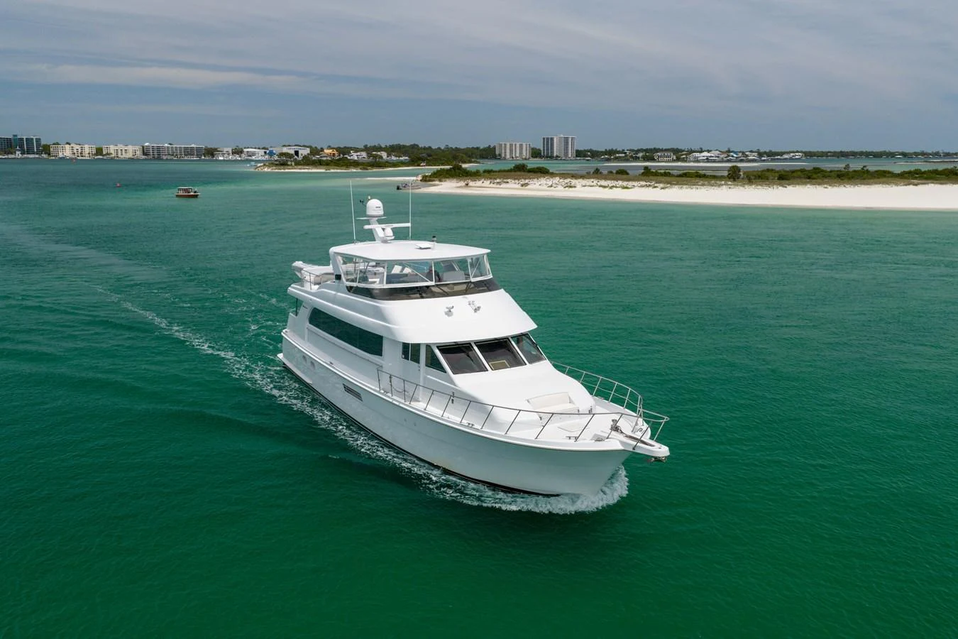 A sleek yacht cruises through clear turquoise waters near a scenic coastline. aboard HAVILAH Yacht for Sale