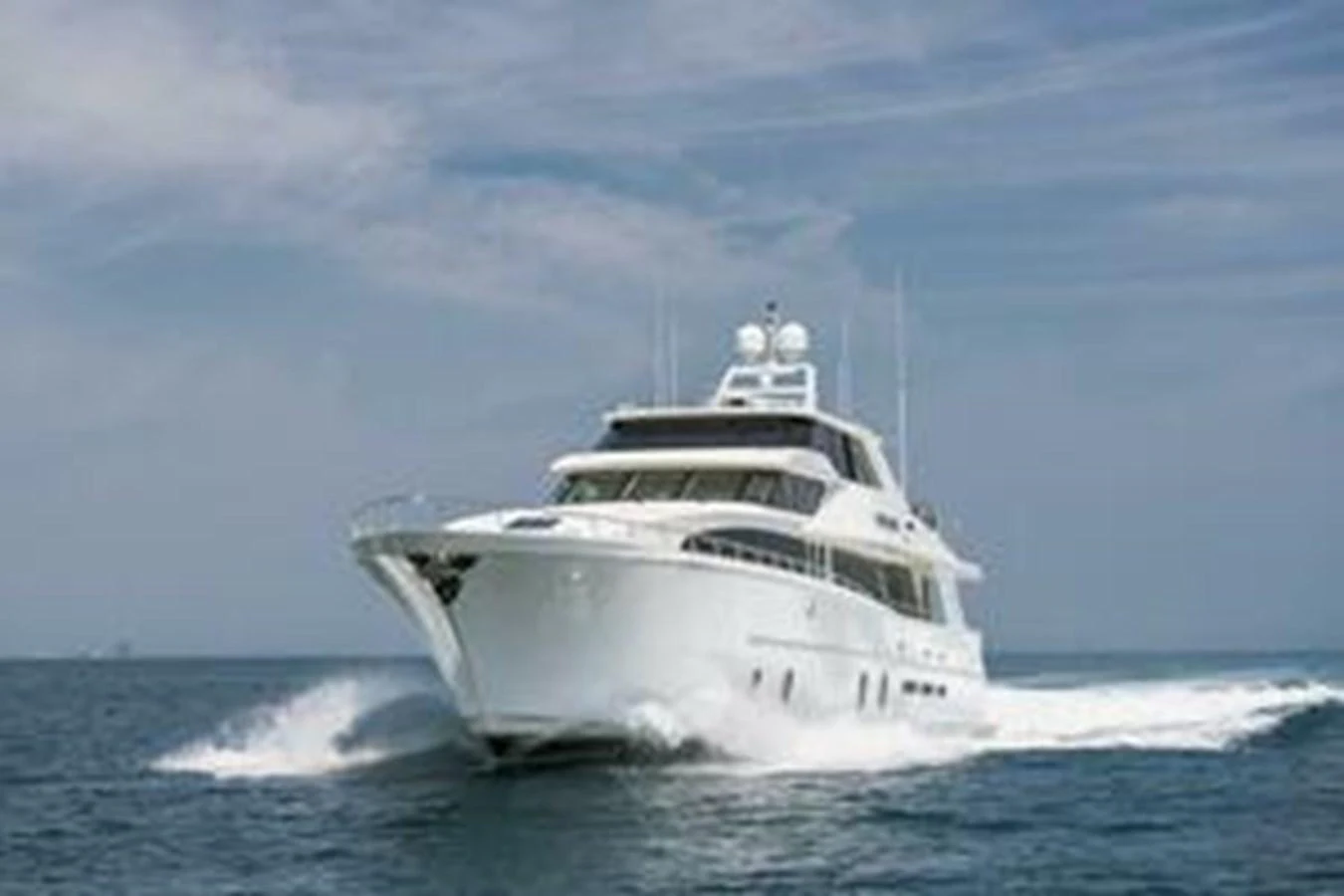 A sleek yacht cruises powerfully through open waters under a clear sky. aboard FOOTLOOSE Yacht for Sale