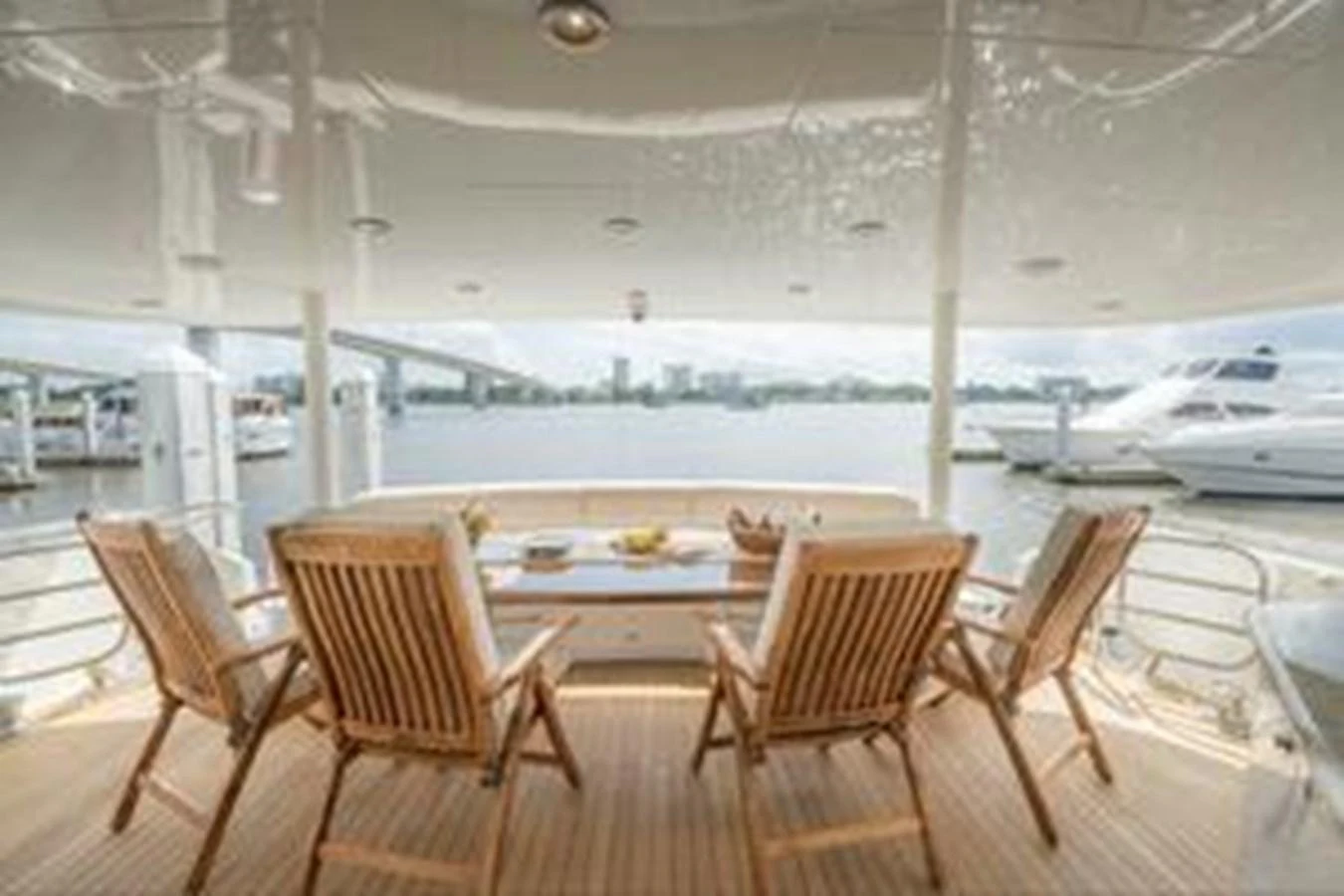 The aft deck features a cozy seating area with wooden chairs, perfect for enjoying the view of the marina. aboard FOOTLOOSE Yacht for Sale