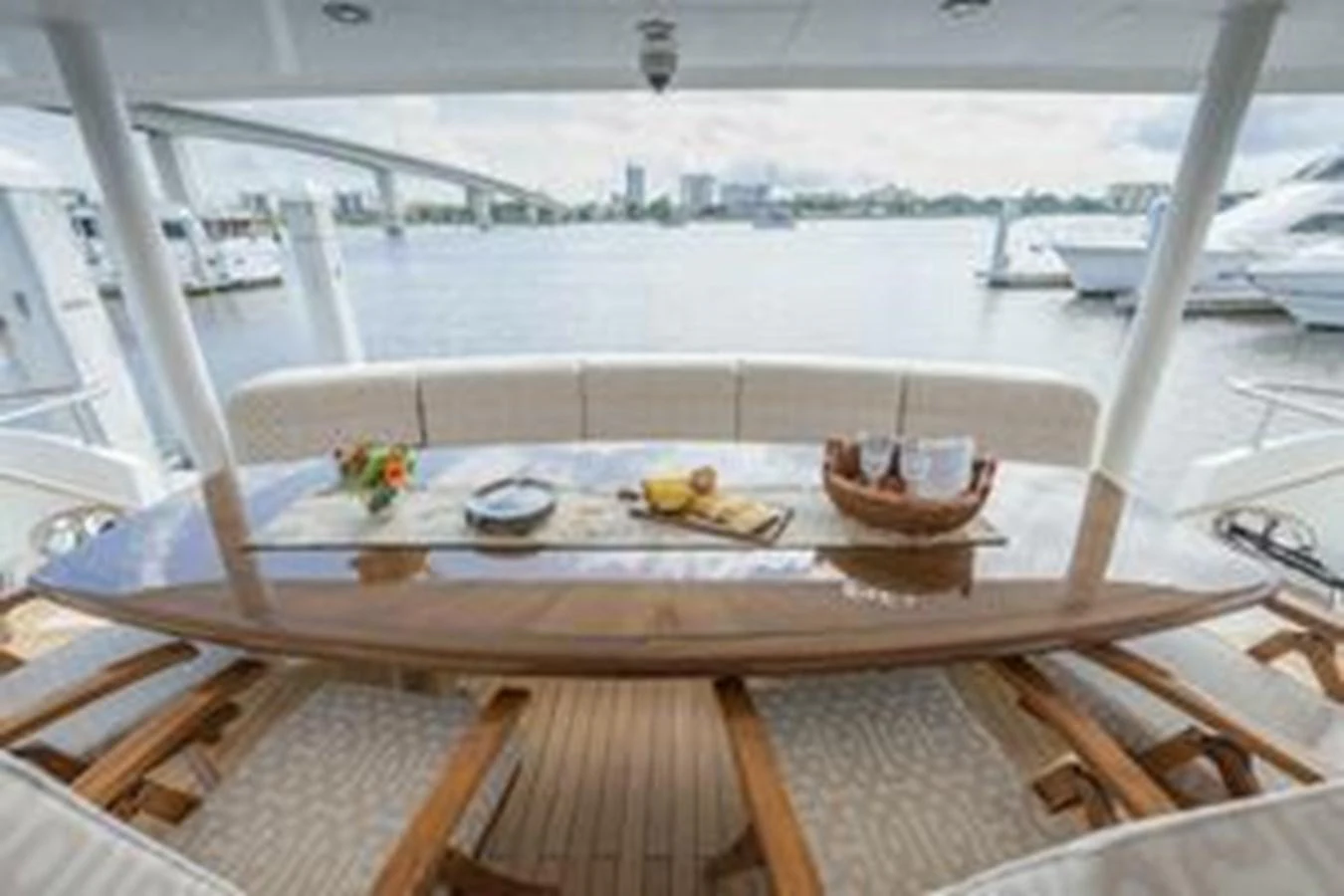 The aft deck features a stylish dining area with a polished wooden table and comfortable seating, offering a scenic view of the marina. aboard FOOTLOOSE Yacht for Sale