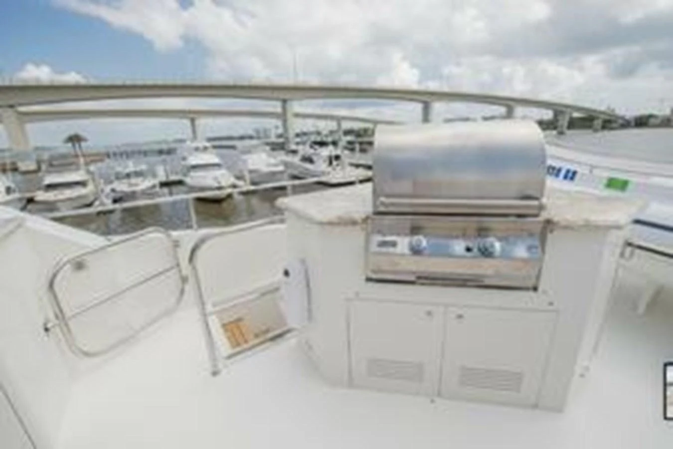 The yacht features a well-equipped grill area with a scenic marina backdrop. aboard FOOTLOOSE Yacht for Sale