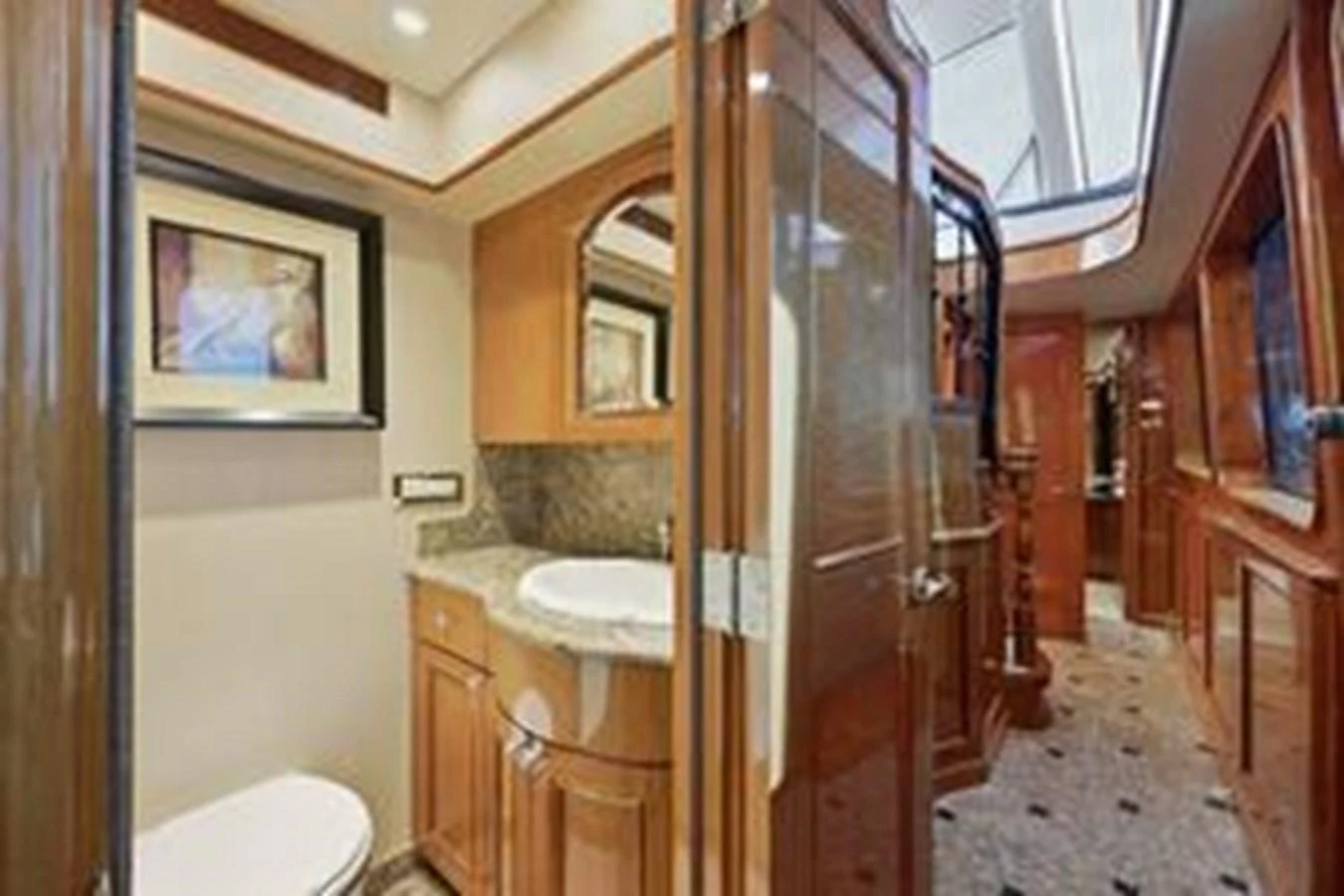 The yacht's bathroom features elegant wood finishes and a skylight for natural lighting. aboard FOOTLOOSE Yacht for Sale