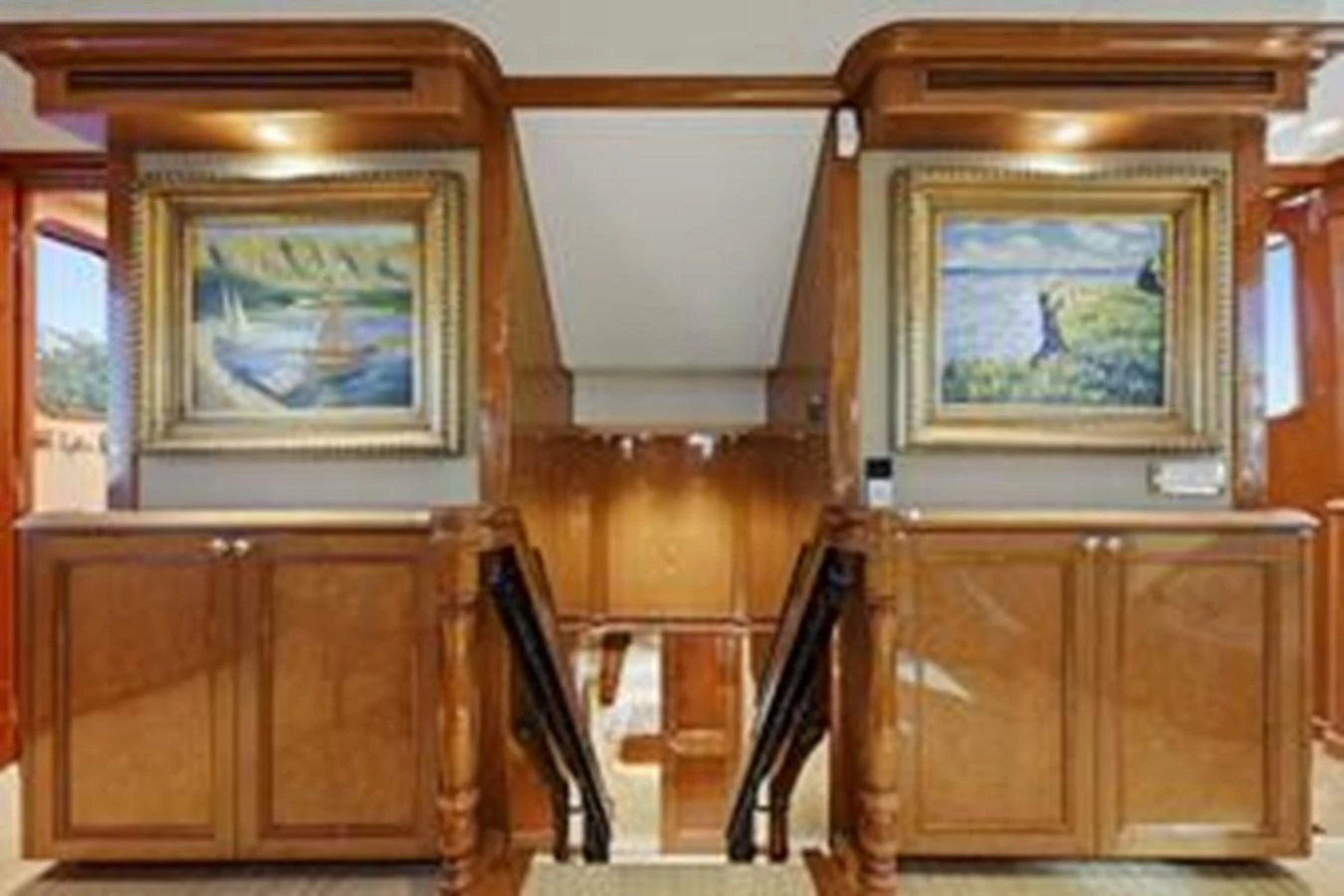 The yacht's interior features a beautifully crafted wooden staircase with framed artwork on the walls. aboard FOOTLOOSE Yacht for Sale
