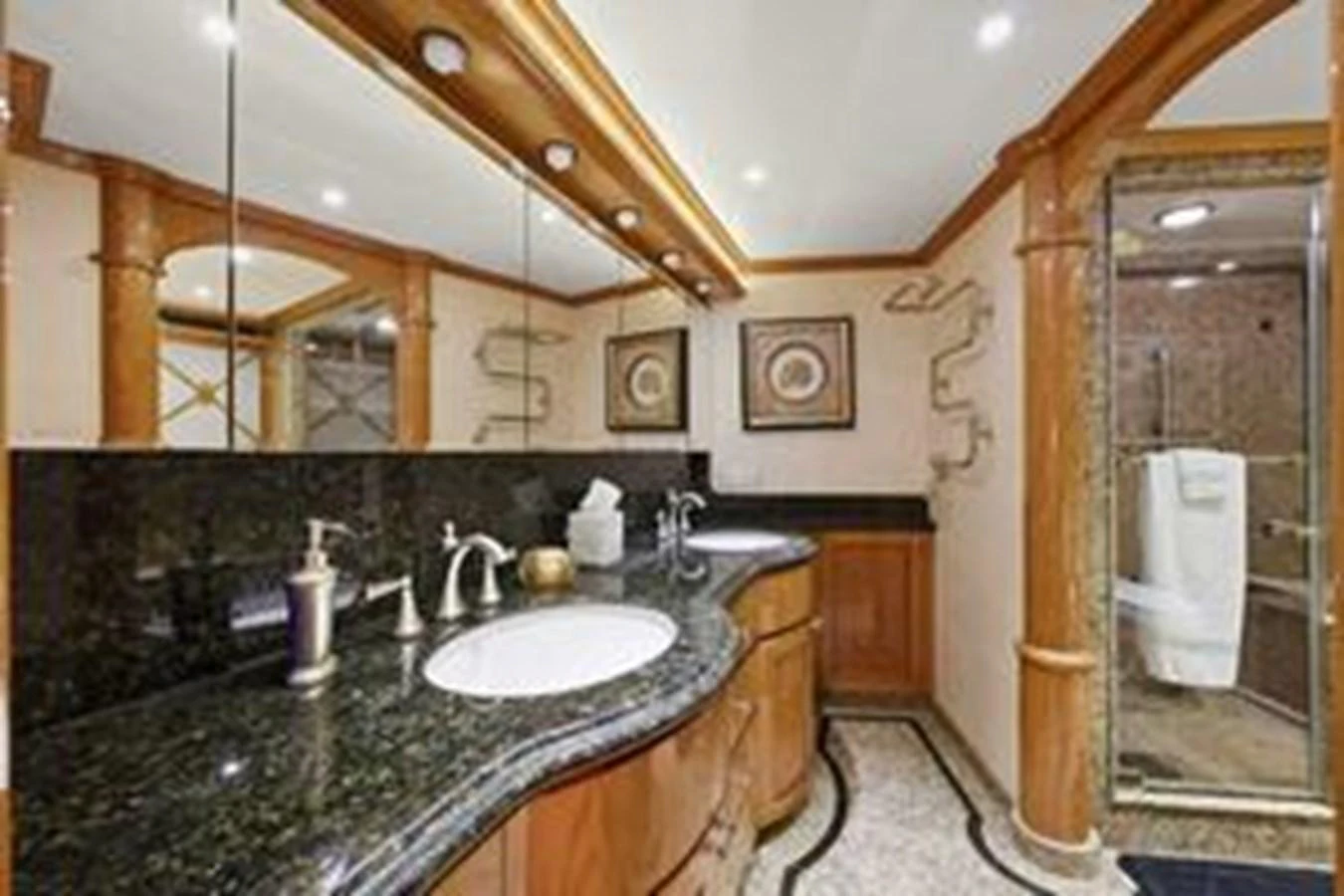 The yacht's bathroom features elegant wood accents, a spacious countertop, and a glass-enclosed shower. aboard FOOTLOOSE Yacht for Sale