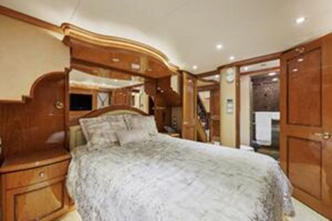 The stateroom features a luxurious bed with elegant wood paneling and ample lighting. aboard FOOTLOOSE Yacht for Sale