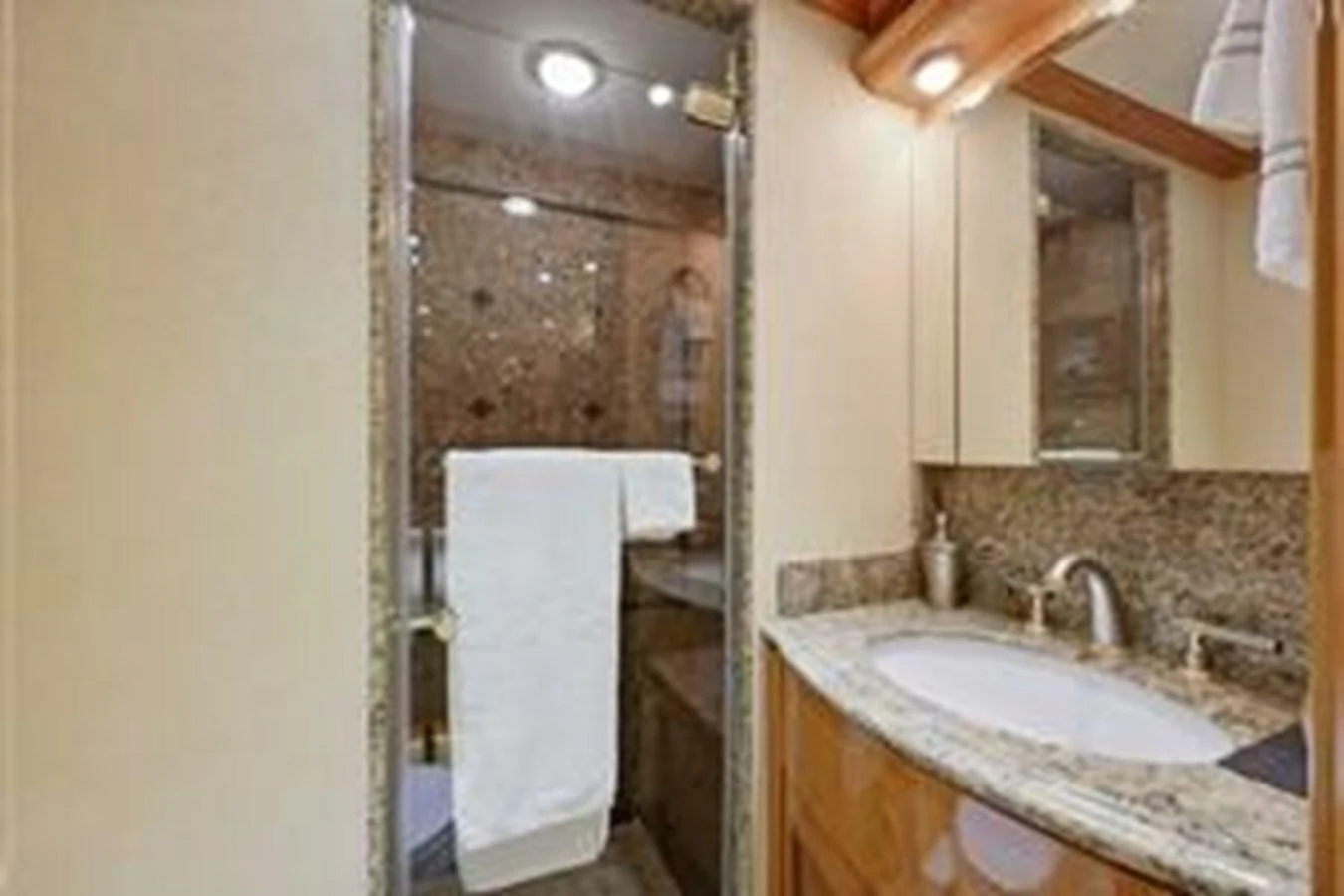 A well-appointed bathroom with a glass-enclosed shower and granite countertops. aboard FOOTLOOSE Yacht for Sale