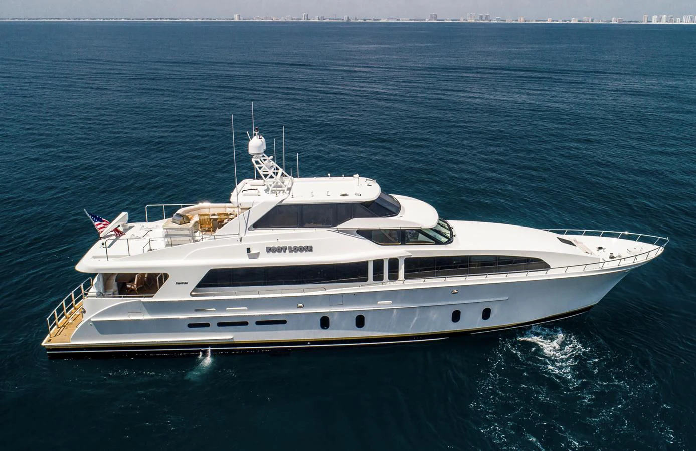 A sleek and elegant yacht cruising on calm waters with a clear skyline in the background. aboard FOOTLOOSE Yacht for Sale
