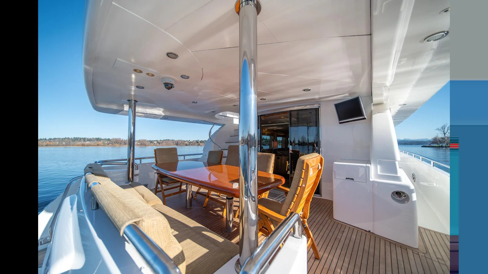 The aft deck features a spacious dining area with comfortable seating and a polished wooden table, perfect for alfresco dining. aboard WISHES GRANTED Yacht for Sale