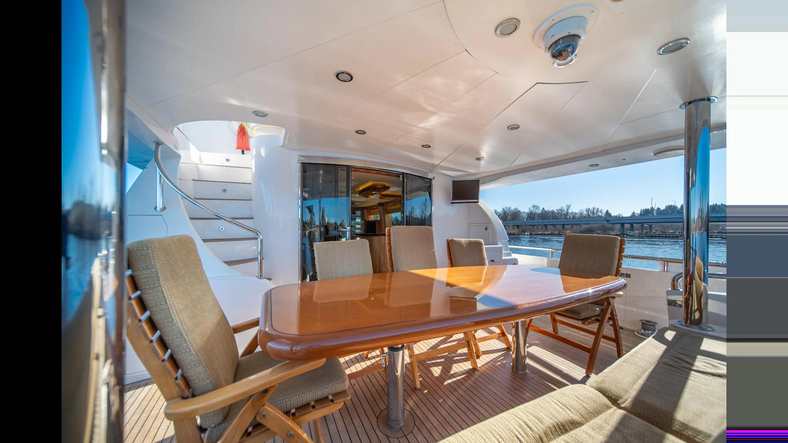 The aft deck features a spacious dining area with a polished wooden table and comfortable seating, perfect for alfresco meals. aboard WISHES GRANTED Yacht for Sale