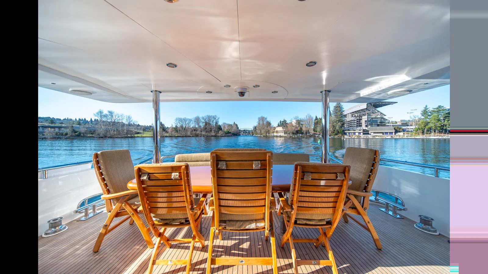 The aft deck features a spacious outdoor dining area with wooden chairs and a scenic view of the water. aboard WISHES GRANTED Yacht for Sale