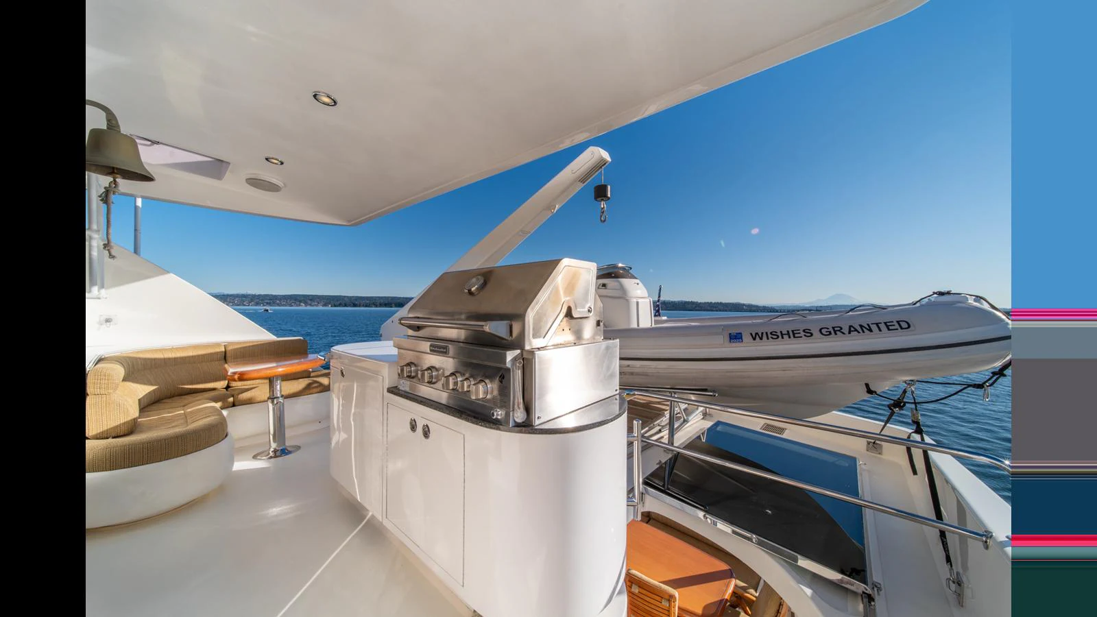 The aft deck features a sleek barbecue grill and a tender, perfect for outdoor dining and water adventures. aboard WISHES GRANTED Yacht for Sale